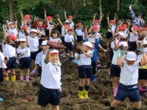 サツマイモを手に笑顔の児童たち