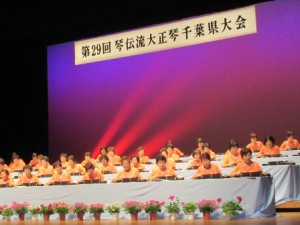 オレンジ色のそろいの衣装で演奏する参加者