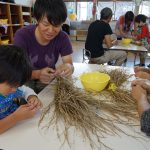 脱穀に挑戦する園児と青年部員(１０月１９日)
