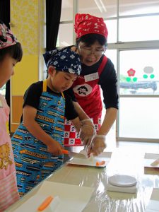 吉田部長と一緒に野菜切りに挑戦する園児(6月6日)