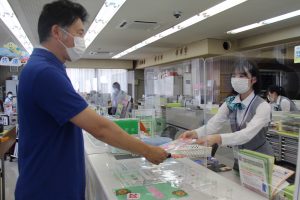 来店客にノベルティを手渡す職員